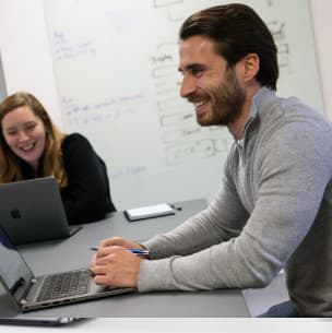 Two people on laptops in a meeting room